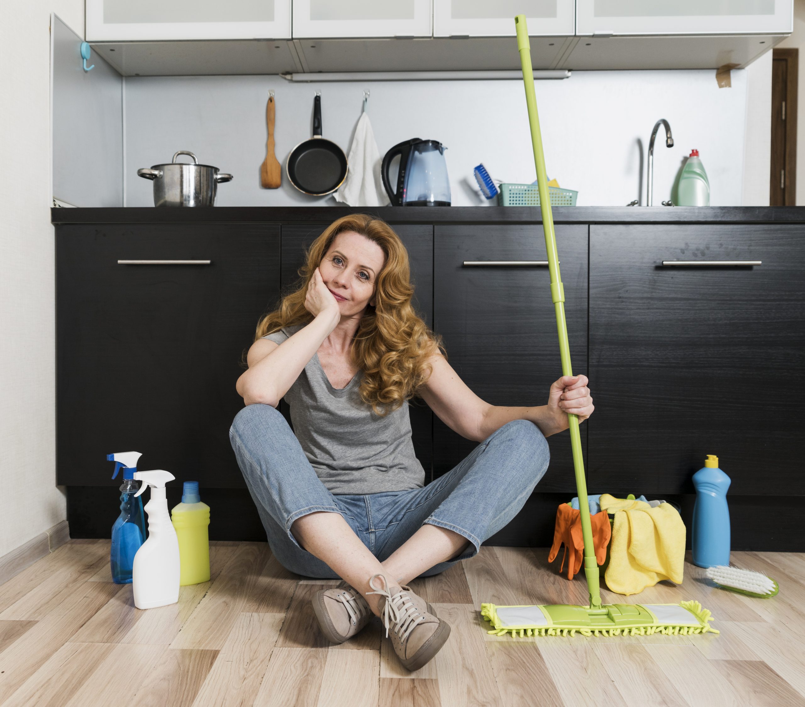 front view woman holding mop with cleaning products
